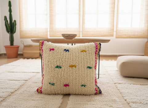 Decorative pillow with colorful embroidered designs on a couch in a living room.