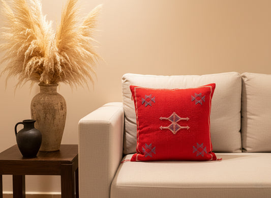 Moroccan red wool pillow on beige sofa with rustic pottery and pampas décor