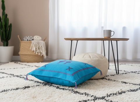 Turquoise Moroccan floor pillow with Berber motifs styled on a neutral rug