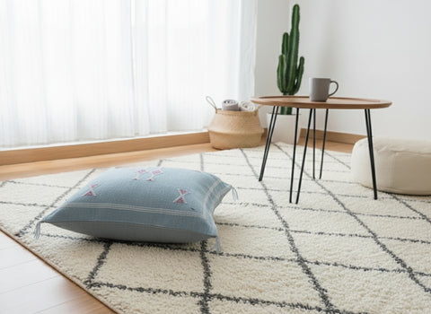 Tanina pillow side view on rug showing detailed Berber motifs and tassels