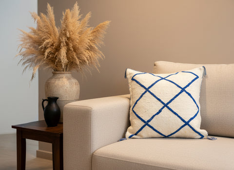 Handwoven Tinessa blue and white Berber pillow on beige sofa