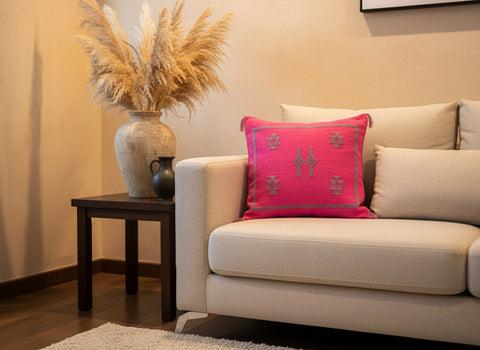Bright pink Taklit Berber pillow on beige sofa with ceramic vase décor
