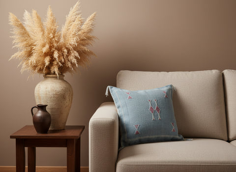 Handwoven Tanina Berber pillow in soft blue with pink embroidery on beige sofa