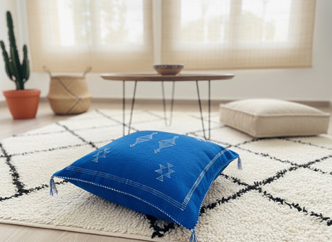 Handwoven blue Berber pillow on Moroccan rug in bright living room