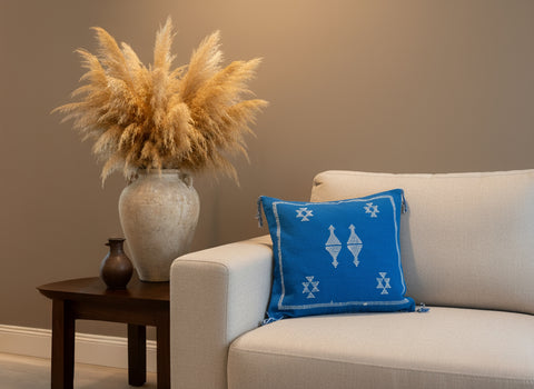 Blue Moroccan Berber pillow with white geometric motifs on beige sofa