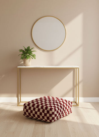 Handmade Moroccan wool pouf placed under a minimal console table in natural light