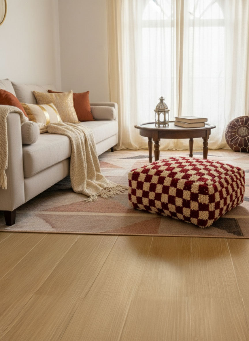 Checker-pattern Berber wool pouf in a warm living room beside a beige sofa