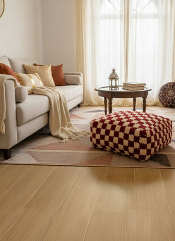 Checker-pattern Berber wool pouf in a warm living room beside a beige sofa