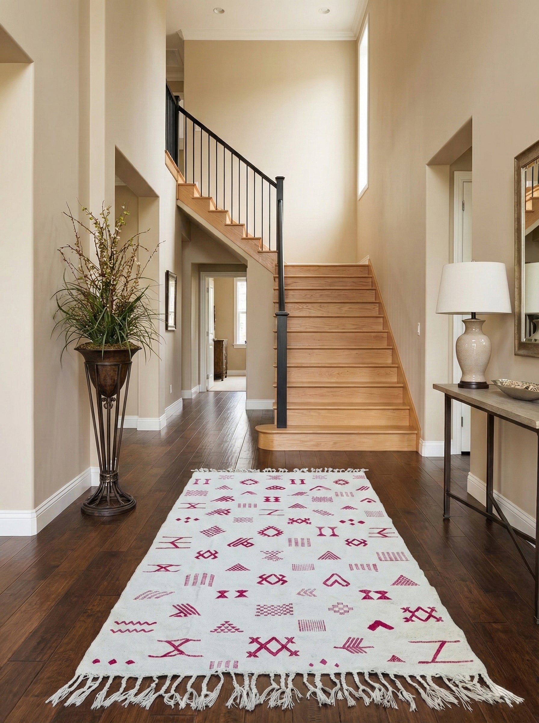 Cream rug with pink motifs styled in an entryway