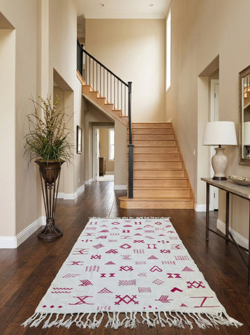 Cream rug with pink motifs styled in an entryway