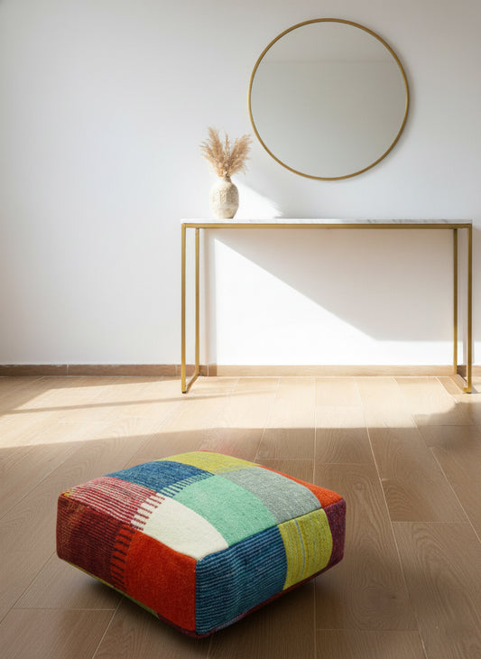 Multicolor Moroccan pouf displayed on a wooden floor under soft natural light.