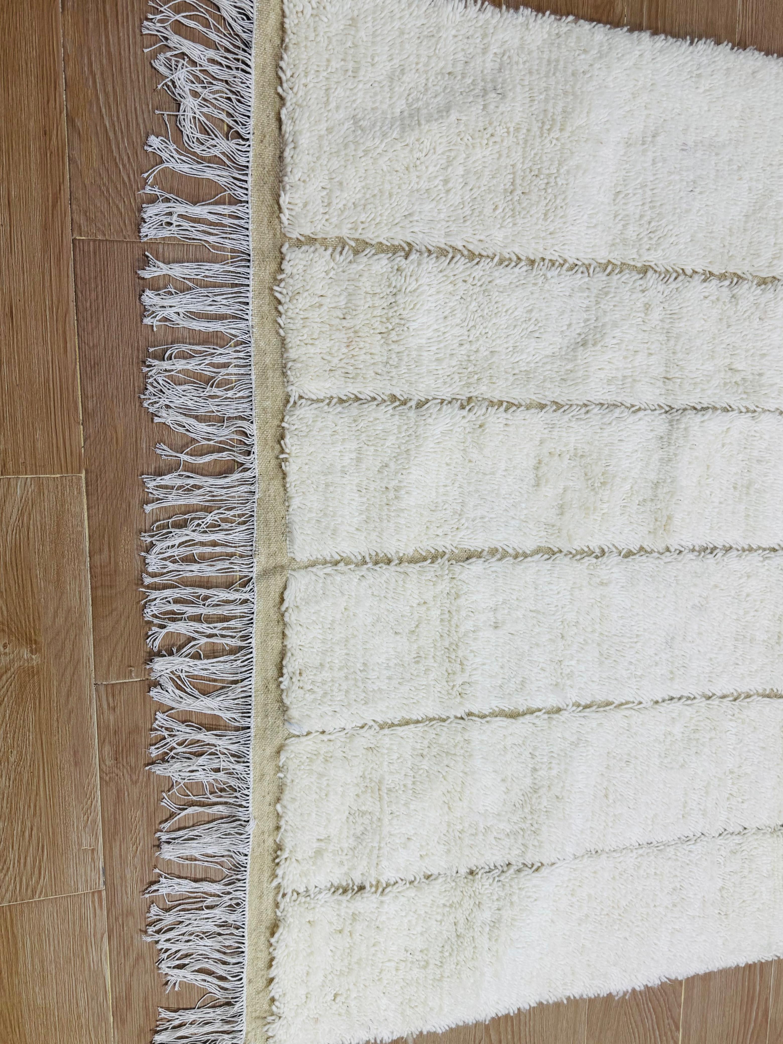 Detailed view of Tazgart handmade rug showing plush cream wool and woven base.