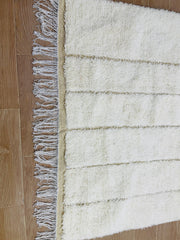 Detailed view of Tazgart handmade rug showing plush cream wool and woven base.