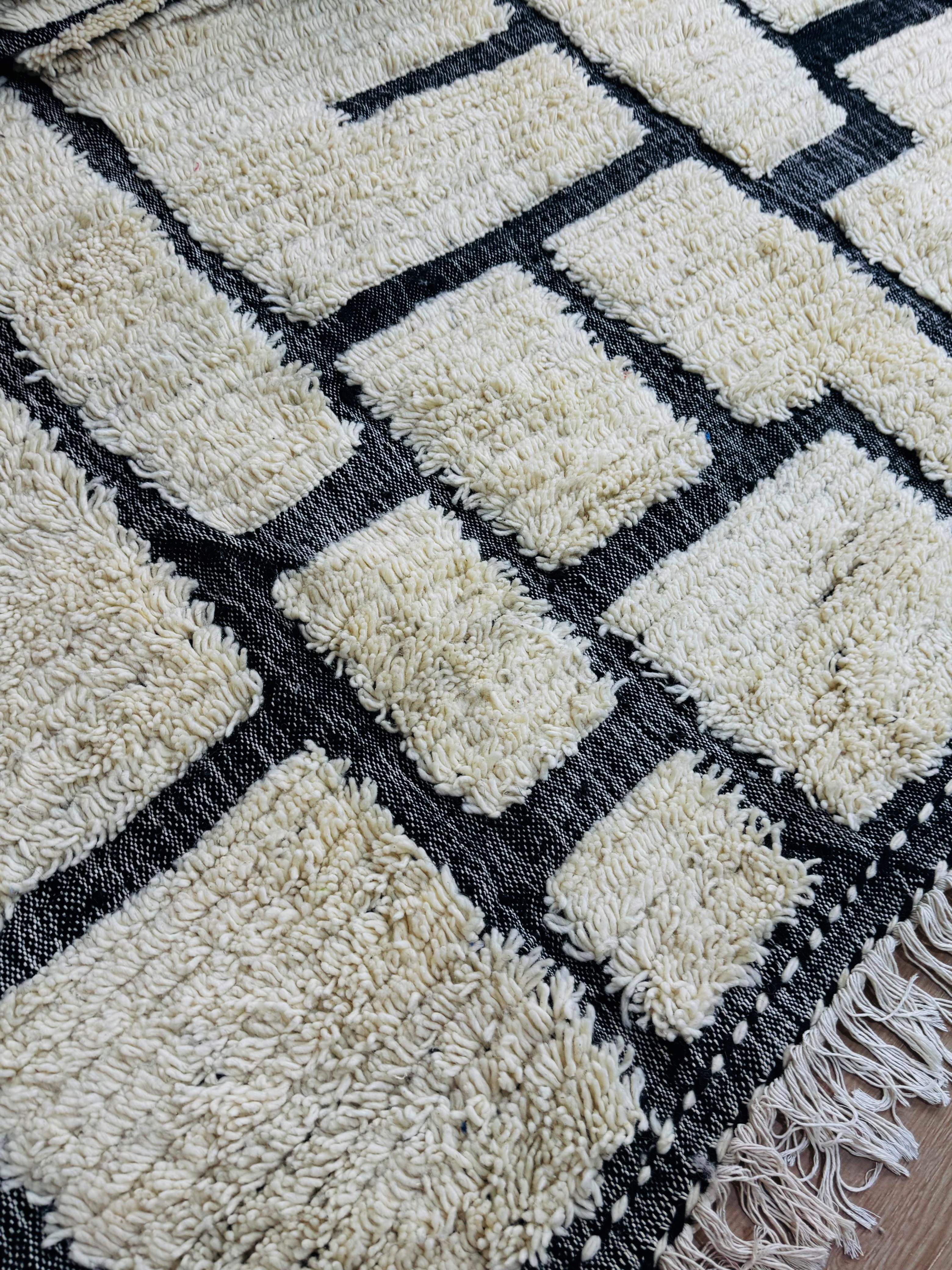 Close-up of Tirina rug texture showing thick cream wool pile and black woven lines