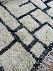 Close-up of Tirina rug texture showing thick cream wool pile and black woven lines
