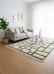 Handwoven Moroccan Tirina rug styled under grey sofa with coffee table