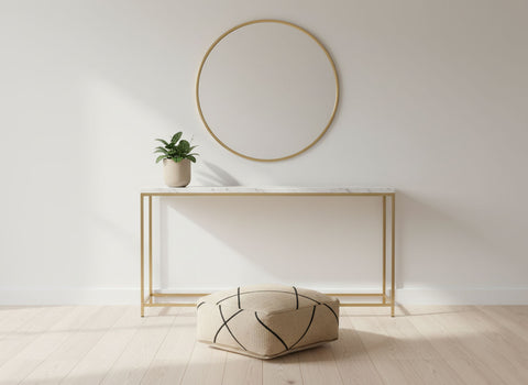 Aytar beige wool pouf displayed in a minimal gold-accent interior