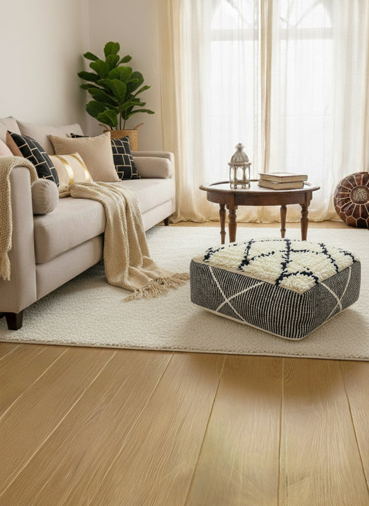 Handmade beige and black Moroccan wool pouf styled in a cozy living room.