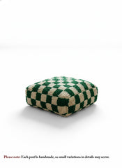Green and cream checkerboard Berber pouf on white background.
