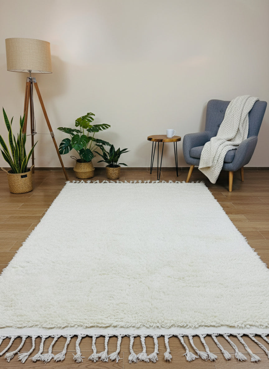 Minimalist beige wool rug with fringe styled beside armchair and plants