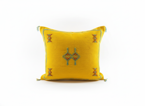 Yellow Moroccan pillow with geometric motifs on a plain white background
