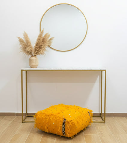 Yellow Berber pouf under a console table with pampas grass decor.
