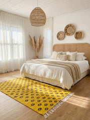 Yellow Tilouin rug placed in a neutral bedroom with woven decor